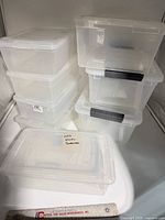 Stacked view of all eight clear plastic containers with lids