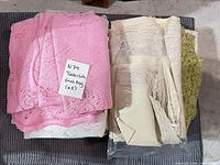 stack of assorted lace table linens in pink, white, cream, beige and green