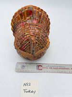 Front view of glazed ceramic turkey-shaped covered dish with ruler for scale