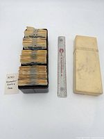 Reels stacked in brown tray with cream lid and ruler for scale