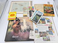 All items laid out: pictorial book, cook book, magazine, language guide, map, brochures, advertisement page