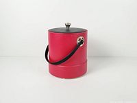 Front view of red plastic ice bucket with black lid, handle down