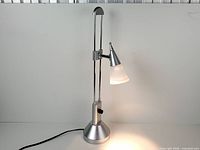 Full view of silver adjustable desk lamp illuminated