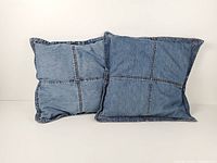Pair of square blue denim patchwork cushions front view