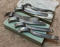 Stacked oyster forks on box with tissue sleeves visible