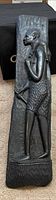 Full view of carved black wood panel showing entire human figure relief
