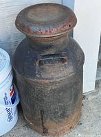 Front view of entire milk can showing cylindrical body and rust patina