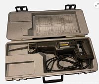 Saw in open molded case showing blade, cord, and spec sheet