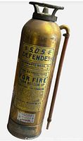 Full view of brass S.O.S. Defender fire extinguisher showing embossed plate and hose