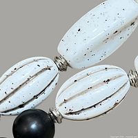 Close-up of white speckled oval beads with metal spacers