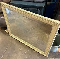 Full front view of rectangular cream frame mirror leaning against wall
