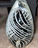 Front view of clear glass paperweight with white spiral and black core