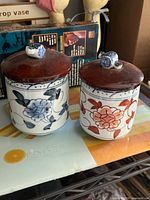 Front view of both jars showing floral designs and lids