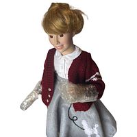 Full view of doll wearing cardigan and poodle skirt, limbs wrapped for protection