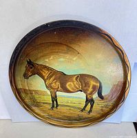 Front of round painted metal tray showing horse and desert scene