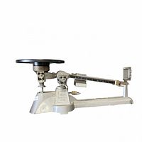 Side view of entire balance beam scale showing base, beam with sliders, and black weighing pan