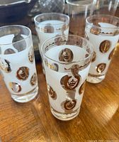 Four matching tumblers on wooden surface, showing gold crown and wreath design on frosted white band