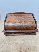Closed jewelry box showing map-print roll-top and brass hardware