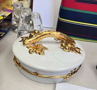 Top view of white porcelain lidded dish with gold gilt branch handle and decorative band