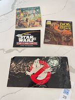 All four items laid out: two Ewoks books, Star Wars manual, Ghostbusters sticker