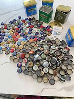 Pile of assorted beer caps with four Twinings tea tins