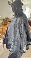Person wearing black exterior silver-lined hooded poncho