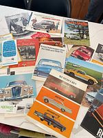 Spread of assorted vintage car brochures and ads