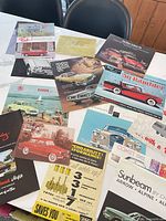Overview of all assorted vintage car brochures spread on table