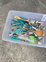 Top view of plastic tub filled with assorted cutlery and utensils