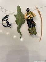 All items laid flat: figure, crocodile, leash, whip