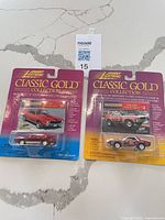 Both sealed Johnny Lightning Classic Gold AMX cars front view