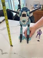 Full view of battle pod toy beside measuring tape showing height and pilot figure