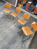 Four plywood and metal school chairs on driveway