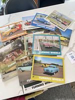 Group of Turning Wheels magazines spread on table, shows quantity and varied covers