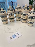 Front view of all five Delft ceramic canisters with lids