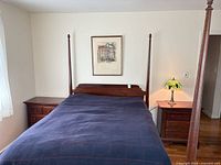 Full view of bed frame between two nightstands with lamp and picture