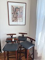 four bar stools with framed print behind