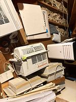 Overview showing window AC unit, Kenmore wall heater panel, portable AC, beige dehumidifiers, blinds and accessories in attic