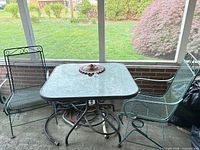 Table, two chairs, sun plaque on tabletop, hose underneath