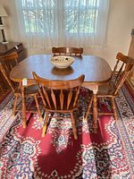 Dining table with four chairs on Oriental rug under window