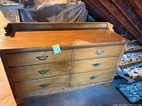 Front view of six-drawer light brown dresser with brass-tone hardware