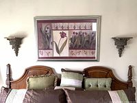 Bedroom wall showing pair of wall sconce shelves flanking framed artwork and headboard