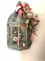 Full view of decorative bird cage showing floral arrangement and bow