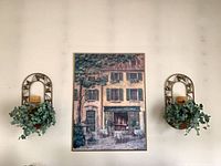 Both sconces mounted on wall flanking artwork