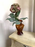 Full view of amber mottled glass vase with artificial hydrangea for scale