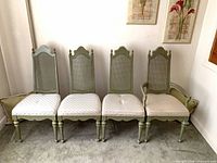 Front view of all four sage green cane-back chairs