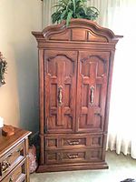 Front view of armoire closed showing paneled doors, brass pulls, lower drawers