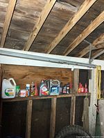 Shelf with oil jugs, aerosol cans, yellow ratchet strap