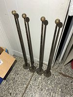 Four brass posts leaning against wall showing overall form