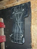 Underside of black plastic creeper showing ribbed structure and four swivel casters